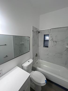 St. Louis apartment for rent - A white toilet with a blue sticker on the lid is in a bathroom with a marble wall and a glass shower door.