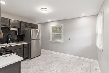 Gary house for rent - A kitchen with a stove top oven and a refrigerator.