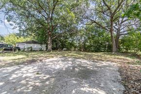 Gary house for rent - A backyard with a dirt ground and trees.