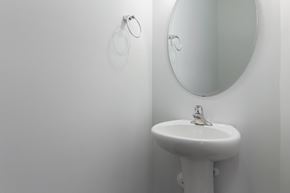 Durham house for rent - A white sink with a round mirror above it.