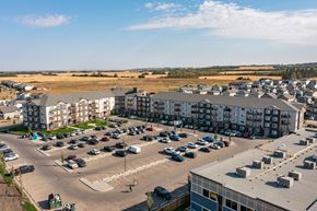 Red Deer apartment for rent - A parking lot with cars and apartment buildings in the background.