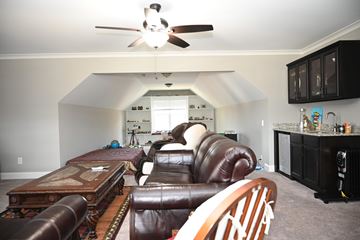 Garner house for rent - A living room with a brown leather couch and a ceiling fan.