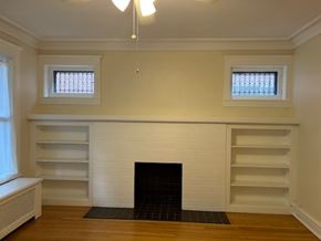 Oak Park apartment for rent - A white fireplace with a black grate in a room with wooden floors and white walls.