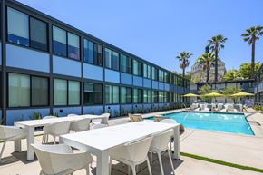 Los Angeles apartment for rent - A poolside table and chairs are set up outside a building.