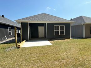 Little Rock house for rent - A house with a grey roof and a white door is surrounded by a grassy area.