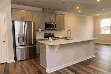 Apex house for rent - A kitchen with a refrigerator, microwave, and stove top oven.