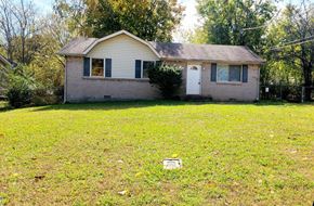 Clarksville house for rent - A small house with a white door and a small window is surrounded by a grassy area.