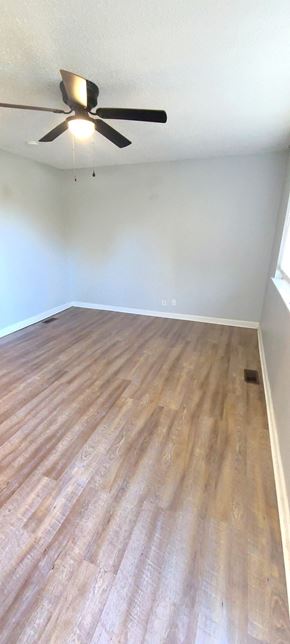 Clarksville house for rent - A room with a ceiling fan and wooden flooring.