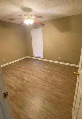 Montgomery house for rent - A room with a ceiling fan and light, wooden flooring, and a white door.