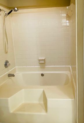 Montgomery house for rent - A white bathtub with a shower head and a white tiled wall.