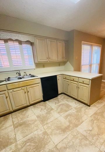 Montgomery house for rent - A kitchen with tan cabinets and a black counter.