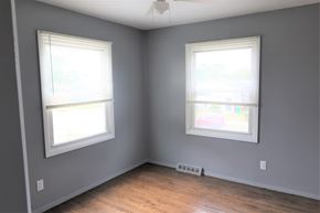Gary house for rent - A room with two windows and wooden floors.