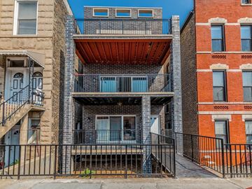 Chicago apartment for rent - A multi-story building with a balcony and a black railing.