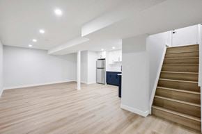Calgary apartment for rent - A spacious room with wooden flooring and a staircase leading to another level.