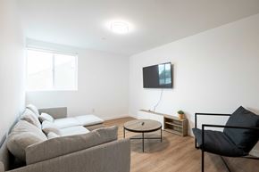 Los Angeles apartment for rent - A living room with a grey couch, a black chair, and a flat screen TV mounted on the wall.