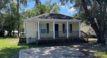 St Augustine house for rent - A small white house with a porch and a tree in front.