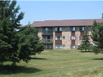 Dewitt apartment for rent - A large building with a balcony is surrounded by trees.