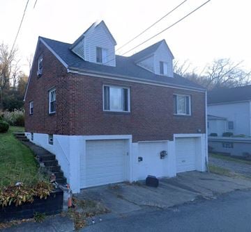 North Versailles house for rent - A red brick house with a white garage door.