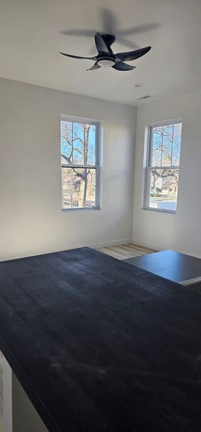 South Bend apartment for rent - A room with a ceiling fan and two windows.