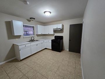 St. Louis house for rent - A kitchen with white cabinets and a black dishwasher.