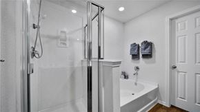 Katy house for rent - A white bathroom with a glass shower stall and a white bathtub.