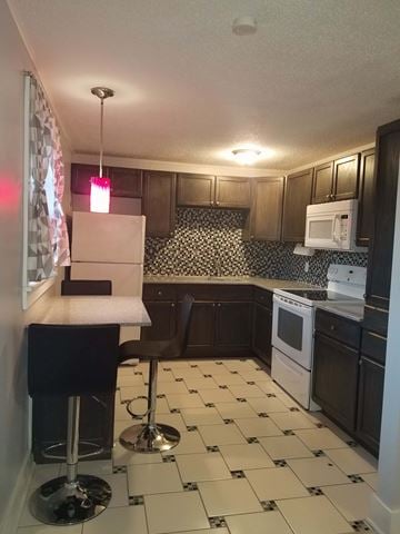 Hattiesburg house for rent - A kitchen with black and white tiles and a white refrigerator.
