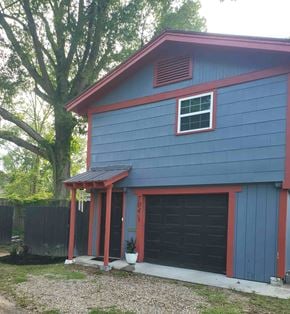 Hattiesburg house for rent - A blue house with a red roof and a black garage door.
