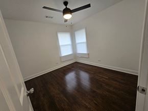 Gary house for rent - A room with a ceiling fan and wooden floors.
