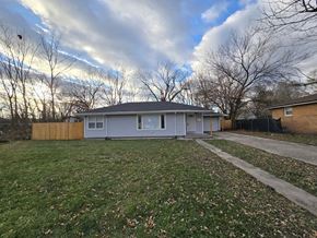 Gary house for rent - A house with a grey roof and a white fence is surrounded by a grassy area with fallen leaves.