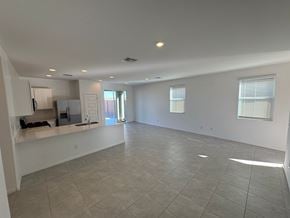 Tolleson house for rent - A spacious empty room with tiled flooring and a kitchen area in the background.