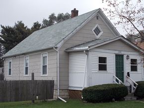 Hammond house for rent - A small white house with a green door and a wooden fence.