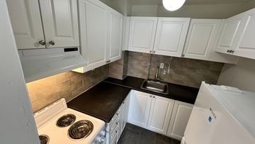 Ottawa apartment for rent - A kitchen with white cabinets and a black countertop.