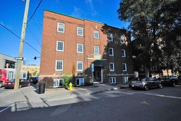 Ottawa apartment for rent - A red brick building with a green roof and a tree in front.