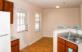 Lubbock apartment for rent - A kitchen with a white fridge, wooden cabinets, and a sink.