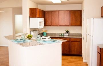 Lubbock apartment for rent - A kitchen with brown cabinets and a white fridge.