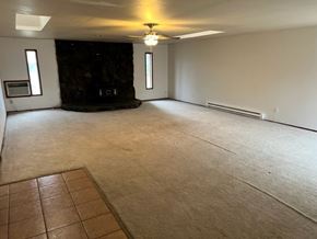 Grandview house for rent - A spacious room with a fireplace and a carpeted floor.