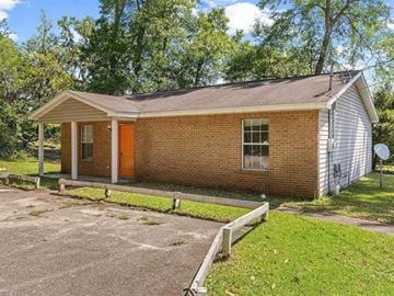 Tallahassee house for rent - A small brick house with a red door and a white fence.