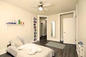 Winnipeg apartment for rent - A bedroom with a bed, a ceiling fan, and a bookshelf.