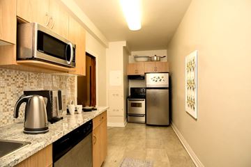 Winnipeg apartment for rent - A kitchen with a stainless steel refrigerator, microwave, and oven.