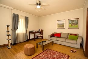 Winnipeg apartment for rent - A living room with a grey couch, a coffee table, a cat tree, and two pictures on the wall.