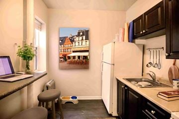 Winnipeg apartment for rent - A kitchen with a white refrigerator and a painting of a building on the wall.