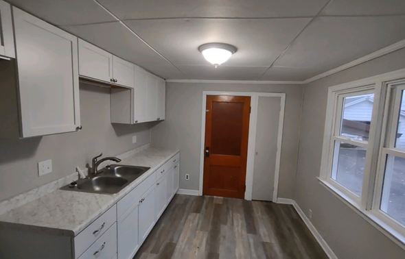 Lima house for rent - A kitchen with white cabinets and a wooden door.