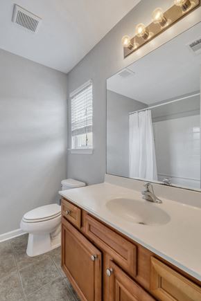 Pooler house for rent - A bathroom with a toilet, sink, and mirror.