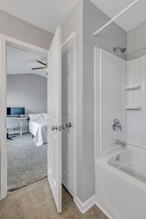 Pooler house for rent - A white bathroom with a tub and a bedroom with a bed and a desk.
