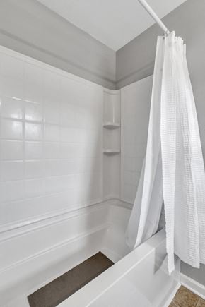 Pooler house for rent - A white shower curtain hangs over a white bathtub.