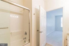 Phoenixville apartment for rent - A bathroom with a glass shower door and a white door leading to a bedroom.
