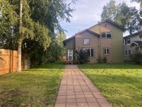 Anchorage house for rent - A house with a brown fence and a green lawn.