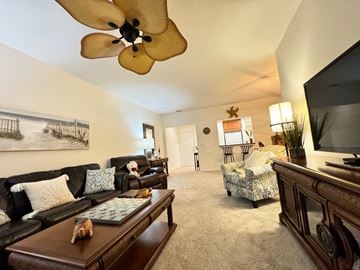 Bradenton house for rent - A living room with a ceiling fan and a painting on the wall.