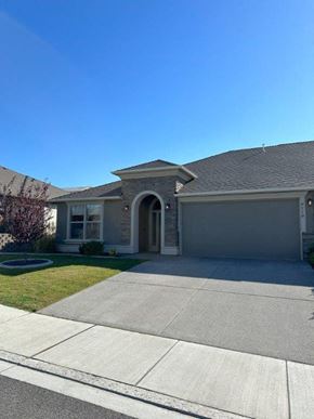 Pasco house for rent - A house with a grey garage door and a brown roof.