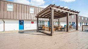 Arlington apartment for rent - A wooden pergola with chairs and a table is in front of a building with a blue door.